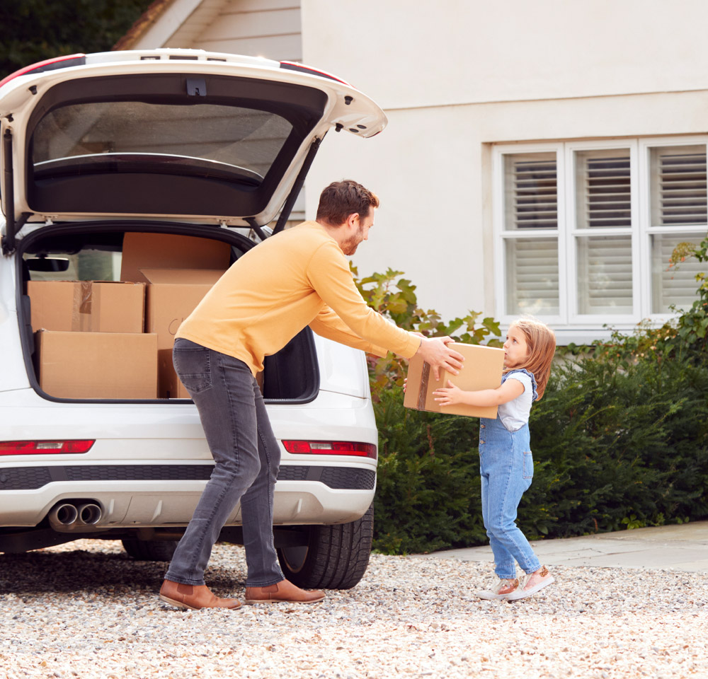 Father handing daughter moving box out of car